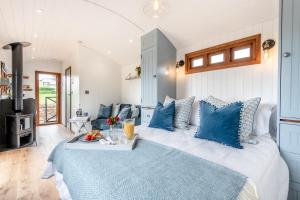a bedroom with a large bed with blue pillows at Daisy Park Shepherds Hut in Looe