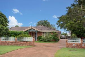 a brick house with a white picket fence at Maroochy Magic Family Coastal Getaway in Maroochydore