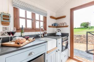 a kitchen with a counter top with a sink and a stove at Daisy Park Shepherds Hut in Looe