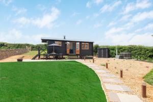 a small black tiny house with a green lawn at Daisy Park Shepherds Hut in Looe