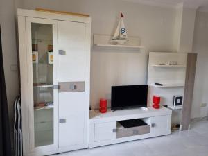 ein Wohnzimmer mit einem TV und einem weißen Schrank in der Unterkunft JAVEA - La Isla in Jávea