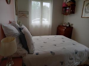 a bedroom with a bed with white sheets and a window at Marie in Mignaloux-Beauvoir
