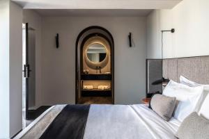 a bedroom with a large bed and a mirror at Nimbus Santorini in Oia