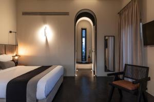 a hotel room with a bed and a chair at Nimbus Santorini in Oia