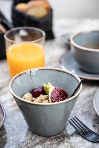 a bowl of cereal with fruit and a glass of orange juice at Nimbus Santorini in Oia