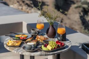 a table topped with plates of food and glasses of orange juice at Nimbus Santorini in Oia