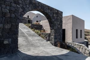 a stone archway leading to a building with a house at Nimbus Santorini in Oia