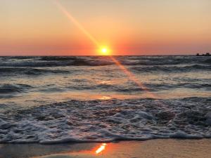 ein Sonnenuntergang über dem Meer mit den Wellen in der Unterkunft Pia Beach House in Bacoli