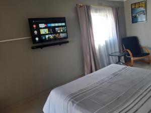 a bedroom with a bed and a tv on the wall at The Private and Cosy Guest House 2 in Germiston
