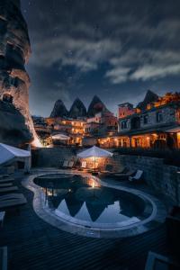 a swimming pool at night with mountains in the background at Aza Cave Cappadocia Adult Hotel in Göreme