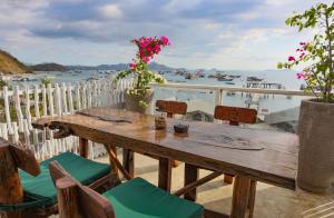 een houten tafel op een balkon met uitzicht op het water bij Eco Tree O'tel in Labuan Bajo