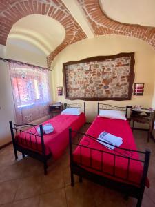 a bedroom with two beds and a brick wall at Orchidea in Carrù