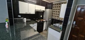 una piccola cucina con armadietti bianchi ed elettrodomestici neri di Executive 2 bed Apartment, free WIFI and DSTV a Johannesburg