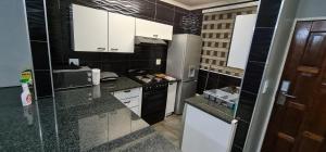 una pequeña cocina con armarios blancos y electrodomésticos negros en Executive 2 bed Apartment, free WIFI and DSTV, en Johannesburgo