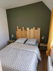 een slaapkamer met een groot bed met een houten hoofdeinde bij Le vent du large in Sangatte