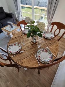 een houten tafel met borden en een vaas met bloemen erop bij Le vent du large in Sangatte