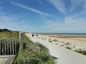 a group of people walking along a sandy beach at Le vent du large in Sangatte