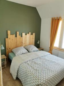 een slaapkamer met een groot bed met een houten hoofdeinde bij Le vent du large in Sangatte