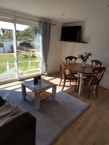 a living room with a table and chairs and a television at Le vent du large in Sangatte