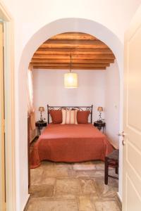 a bedroom with a red bed with an archway at Tinos Cycladic house in Kariá