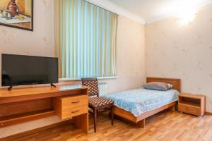 a bedroom with a bed and a flat screen tv at гостевой дом "Максим" in Novomikhaylovskiy