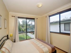 a bedroom with a bed and a large window at Pet Friendly on Pelican Close to Myall River in Hawks Nest