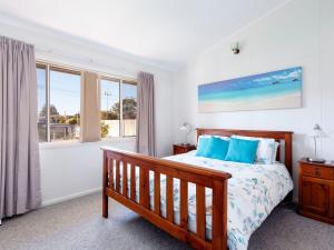 a bedroom with a bed with blue pillows and a window at Surfs Up in Hawks Nest