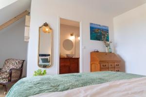 a bedroom with a bed and a mirror and a dresser at La Bellevue Bréville - B&B in Bréville-sur-Mer