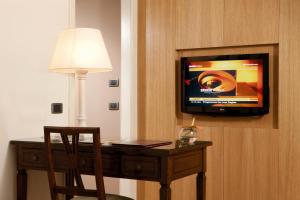 a desk with a chair and a television on a wall at Park Hotel Villa Grazioli in Grottaferrata