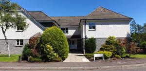 a large white house with bushes in front of it at Strathallan - Luxury 3 Bedroom Apartment, Gleneagles, Auchterarder in Auchterarder