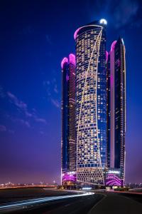 Un grand bâtiment avec des lumières violettes la nuit dans l'établissement Paramount Hotel Dubai, à Dubaï