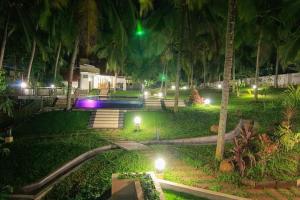a park with palm trees and lights at night at Aanandakosha Ayurveda Retreat in Trivandrum