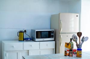 a kitchen with a microwave and a refrigerator at Judith Home FIKA CAFE in Kigali