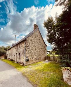 an old stone building with a fence and a tree at Le Boulay in Guichen