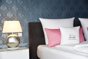 a bed with pink and white pillows and a lamp at Antike & Modern DELUXE in Günzburg