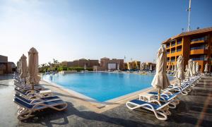 Cancun Sokhna Resort & Villas في العين السخنة: صف من كراسي الصالة والمظلات في المسبح