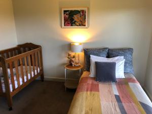 a bedroom with a bed and a crib and a lamp at Harbour Lookout in Strahan