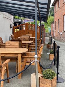 um grupo de mesas e cadeiras de madeira sob um guarda-sol em Old New Inn, Llanfyllin em Llanfyllin