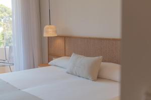 Cama con sábanas blancas y almohadas junto a una ventana en Hotel Serawa Moraira, en Moraira