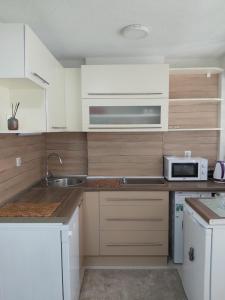 cocina con armarios blancos, fregadero y microondas en Apartman Alma, en Bihać