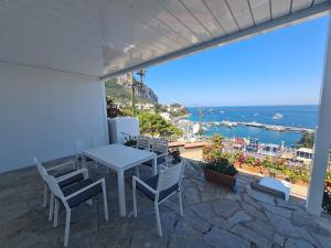 een patio met een tafel en stoelen en de oceaan bij Casa Capri Me in Capri