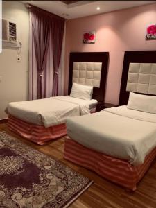 1 dormitorio con 2 camas y alfombra en شاليهات شاطئ ارينا en Qarār