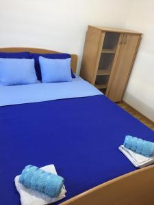 a bed with blue sheets and blue pillows on it at Apartman Tami in Doboj