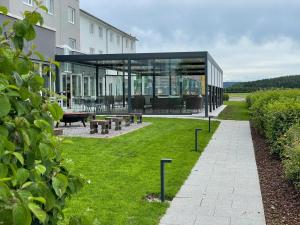 a building with a glass extension with a lawn at Concorde Hotel am Flugplatz in Donaueschingen