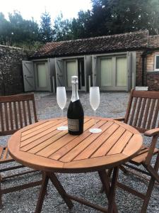 una botella de vino en una mesa de madera con 2 copas de vino en Quantock House Lodge, en Holford