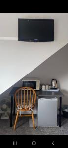 uma cadeira sentada em frente a uma mesa com uma televisão em Caversham Lodge em Reading