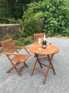 a wooden table with two chairs and a bottle of wine at Quantock House Lodge in Holford