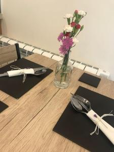 una mesa con un jarrón de flores y un tenedor y un cuchillo en Quantock House Lodge, en Holford