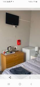 a bedroom with a bed and a tv on the wall at Caversham Lodge in Reading