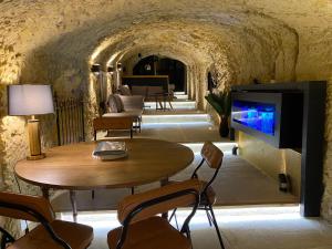 un salon avec une télévision, une table et des chaises dans l'établissement Le Tunnel du Moulin, à Noyers-sur-Cher